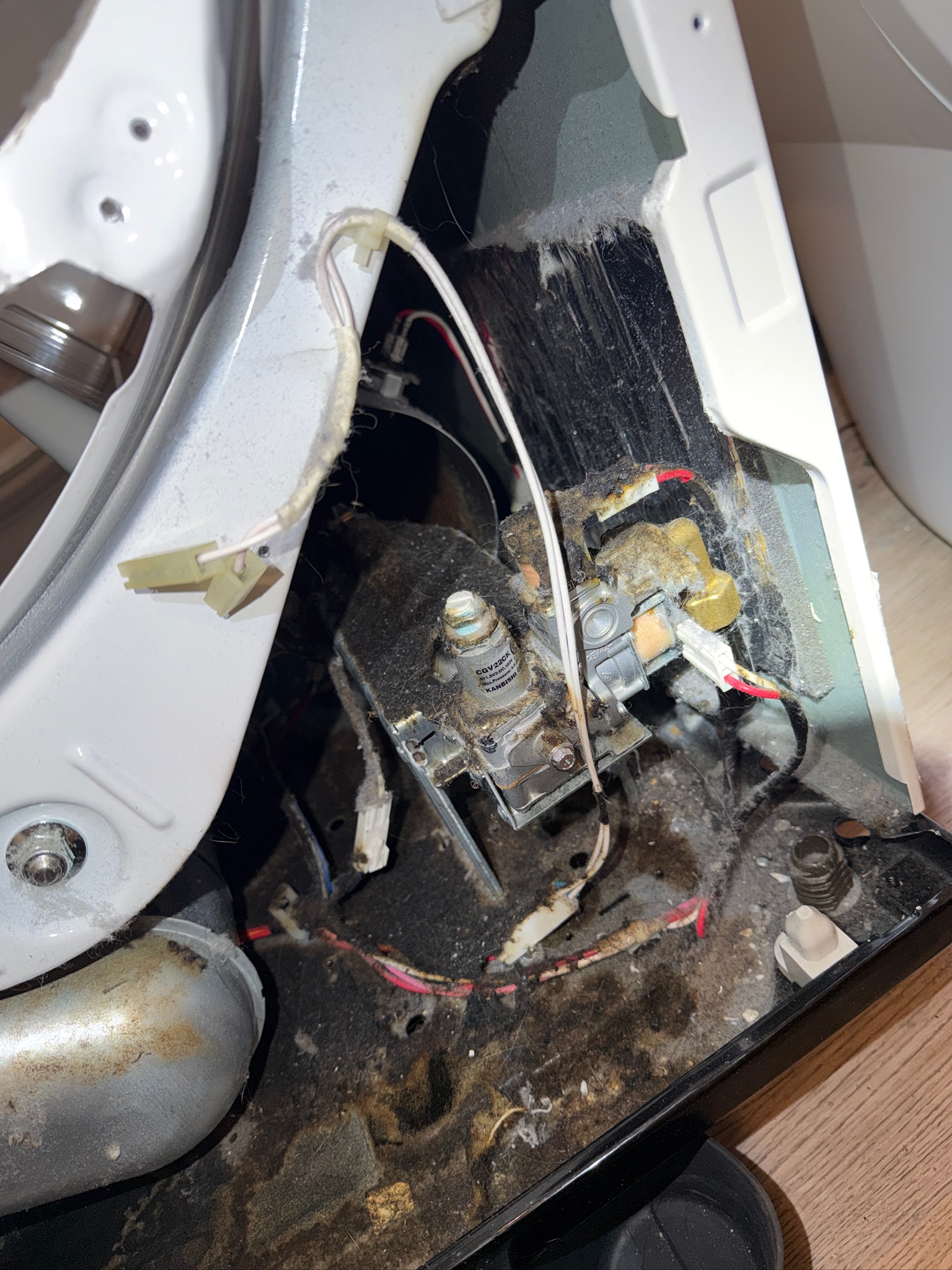 Inside of a dryer before cleaning showing heavy lint and debris buildup on components